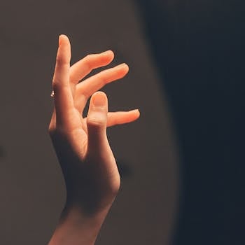 Elegant human hand reaching into soft, warm light creating a serene and artistic effect.